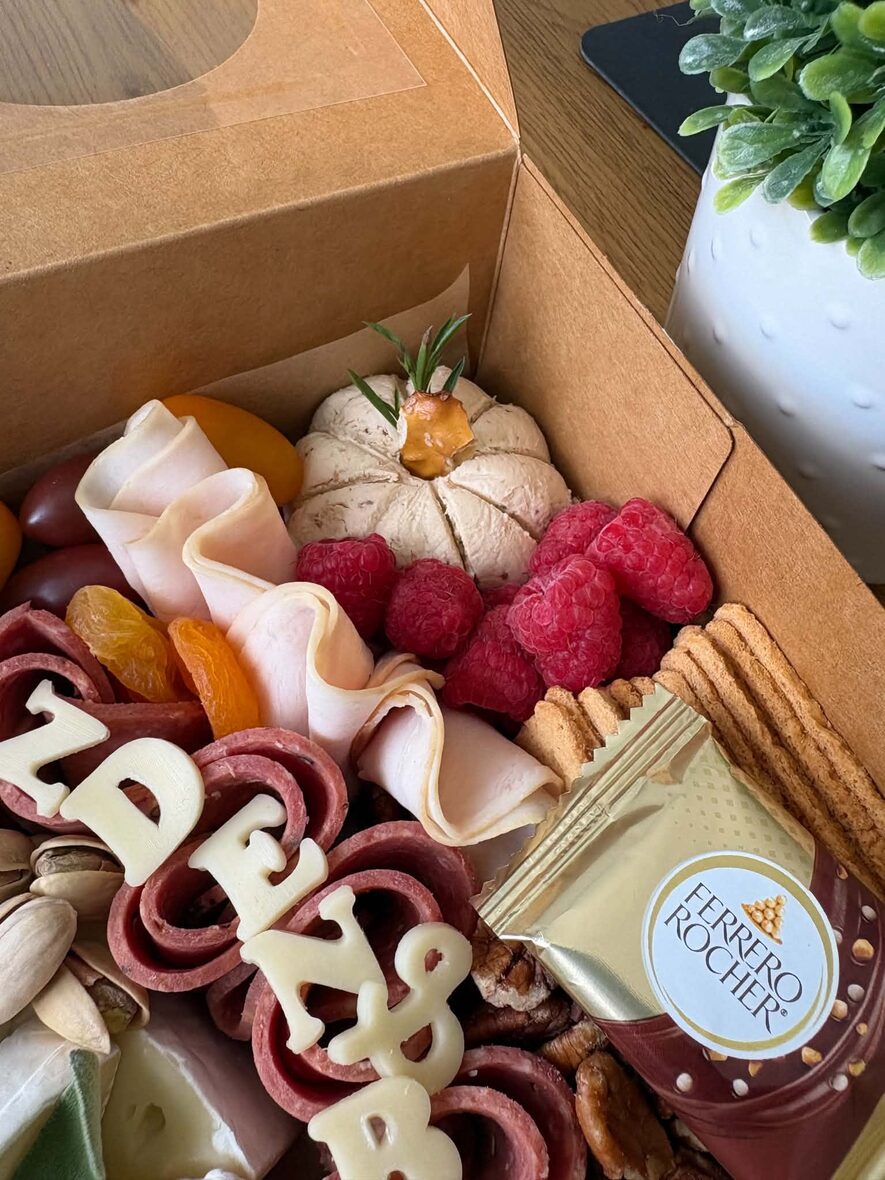 Large grazing box full of cheese, halal charcuterie, fruit, nuts and crackers on a wooden table